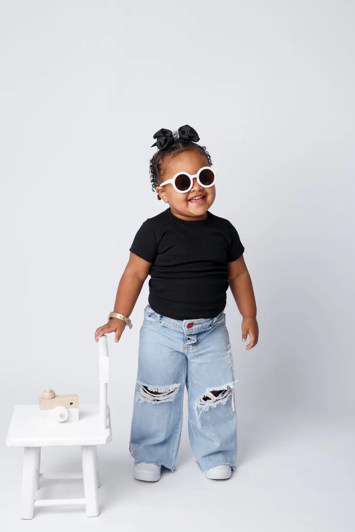 Criança de óculos e roupa preta em ensaio infantil
